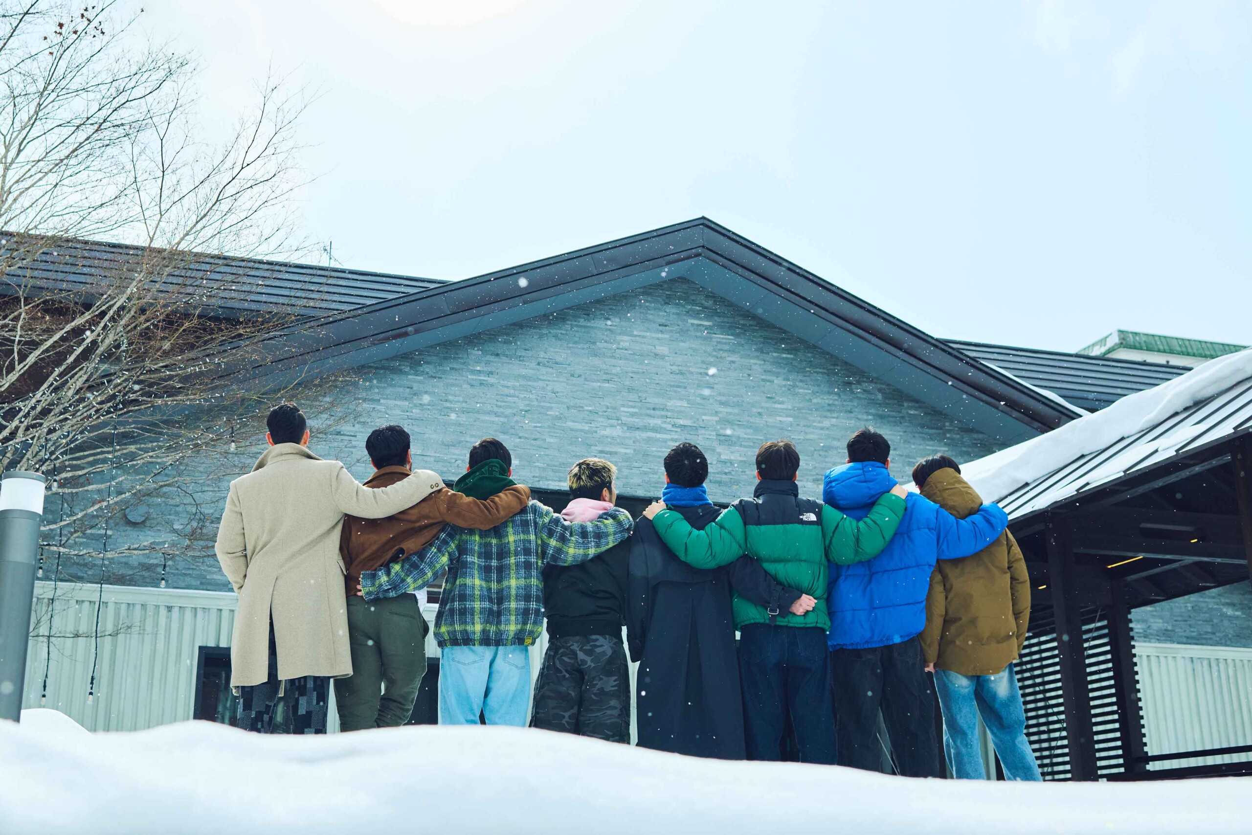 Cast of Netflix’s The Boyfriend standing arm in arm in the snow outside a lodge in Hokkaido.