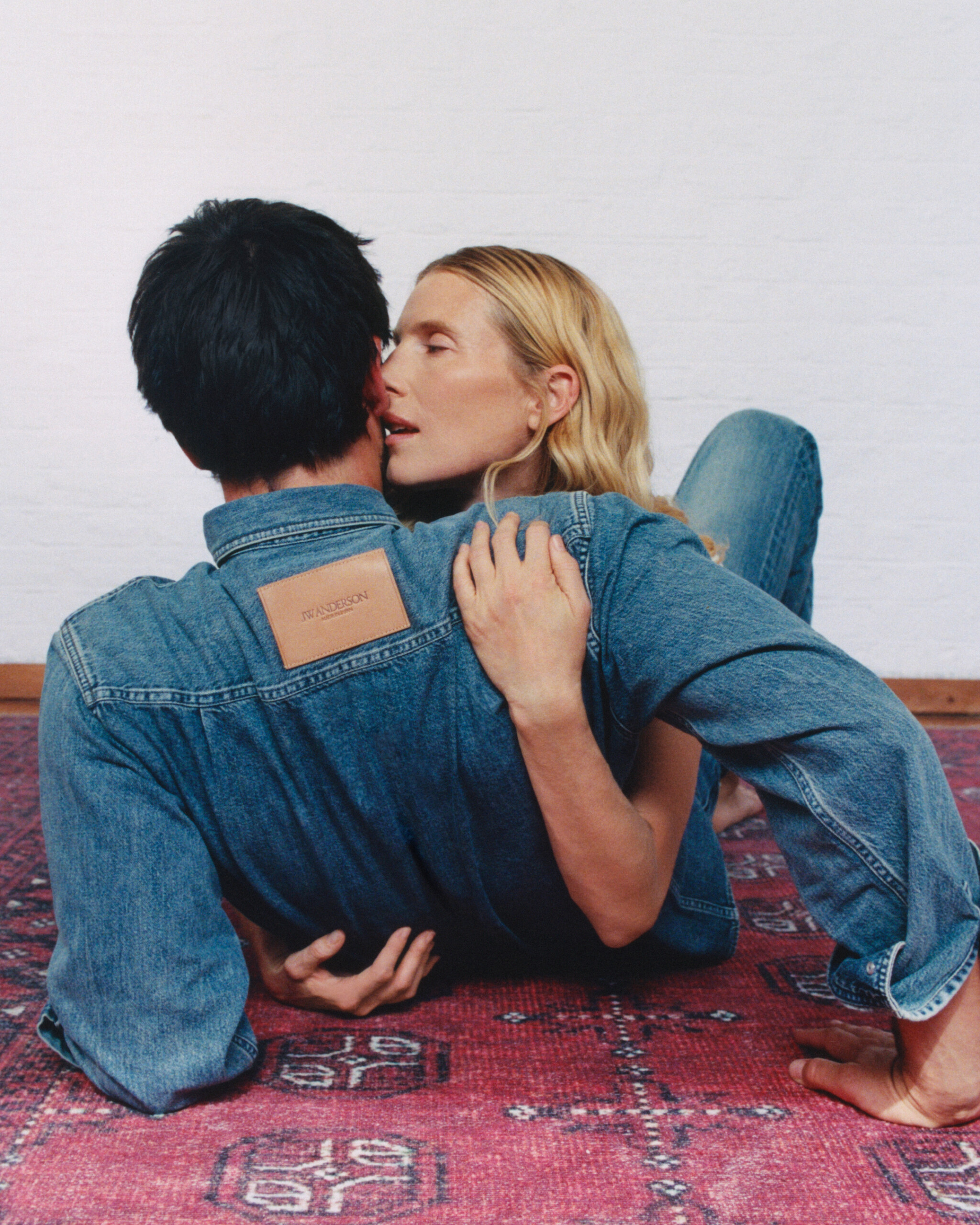 Dree Hemingway and Nick Delli Santi on a rug in matching JW Anderson denim shirts, leather logo patch at the back