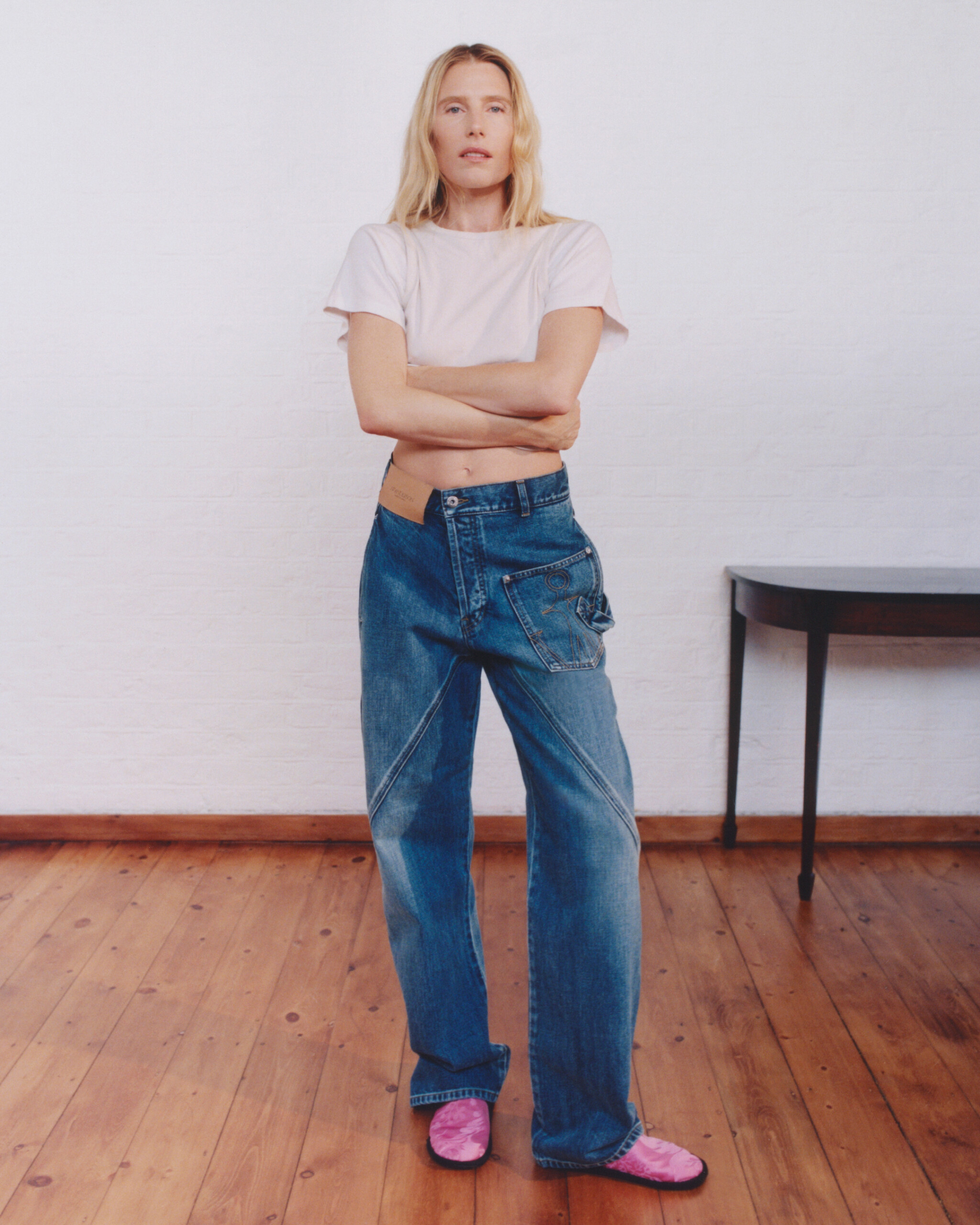 Dree Hemingway with arms crossed in mid-blue JW Anderson Twisted Denim jeans